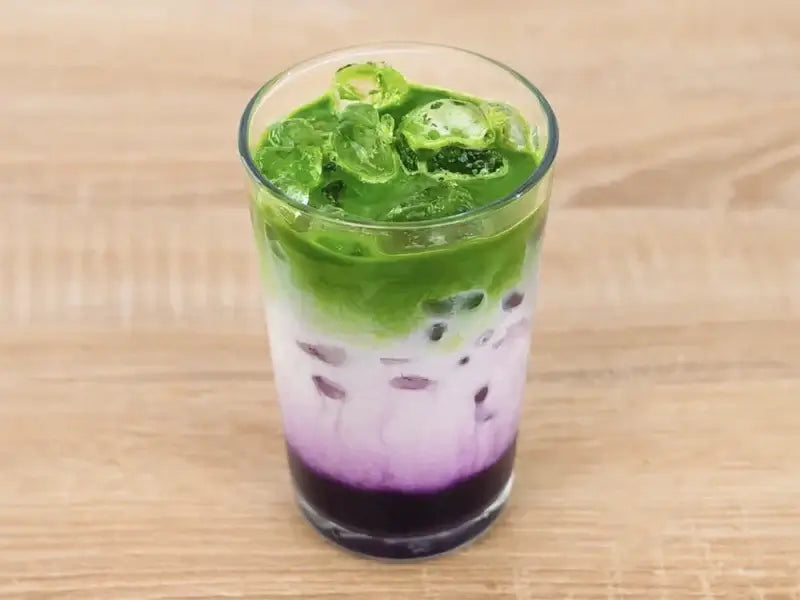 Blackberry matcha latte in a tall glass with ice