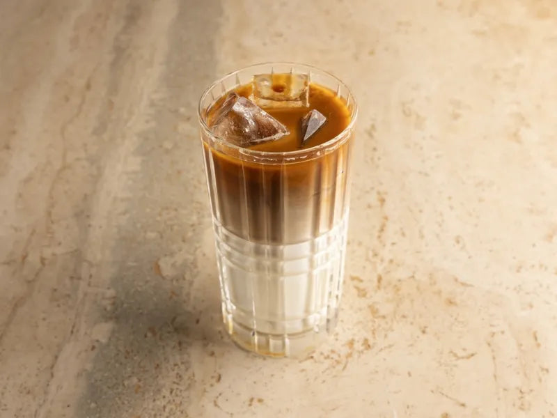 Specialty iced Spanish latte served in a clear glass with layered espresso and milk in a modern Dubai café setting